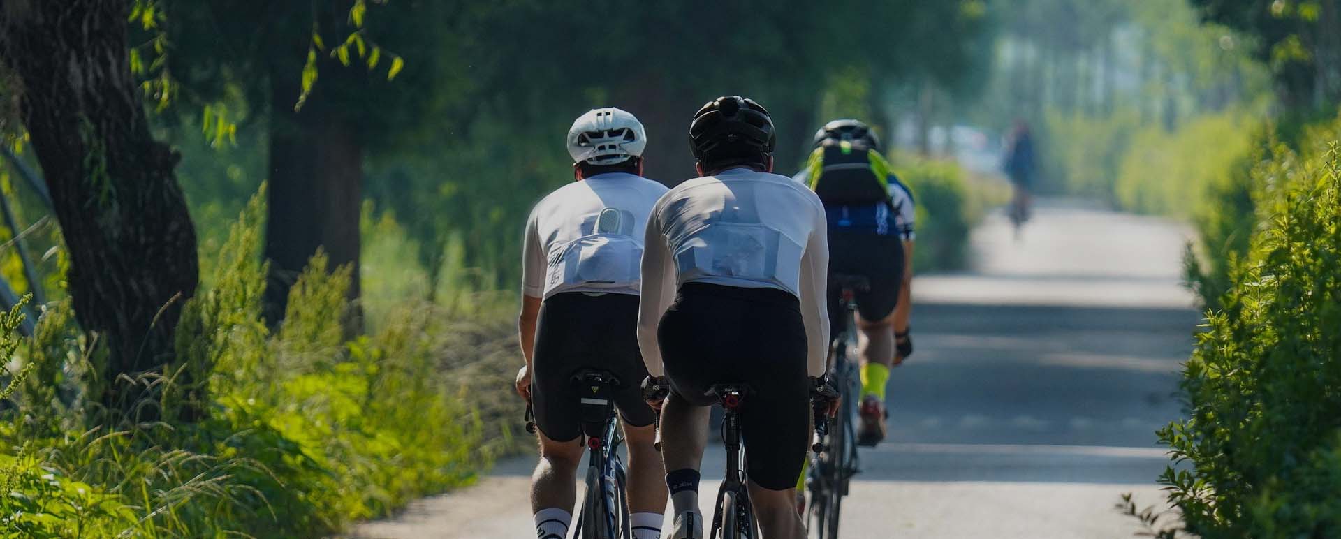 Cyclists riding on a green park road — active life supported by continuous monitoring
